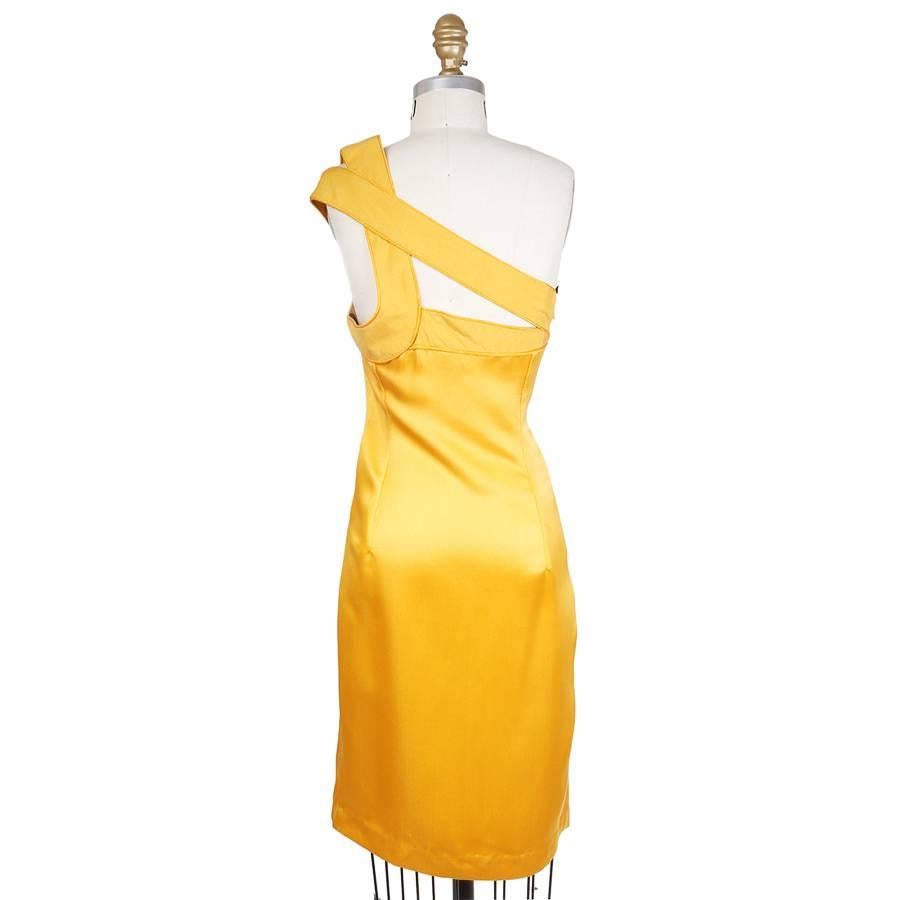 This is a dress by Todd Oldham from spring 1998.  It is made from a yellow silk that is smooth surfaced around the body but with piping and a dupioni finish around the bust.  The one shoulder also features large strips that layer over each other to