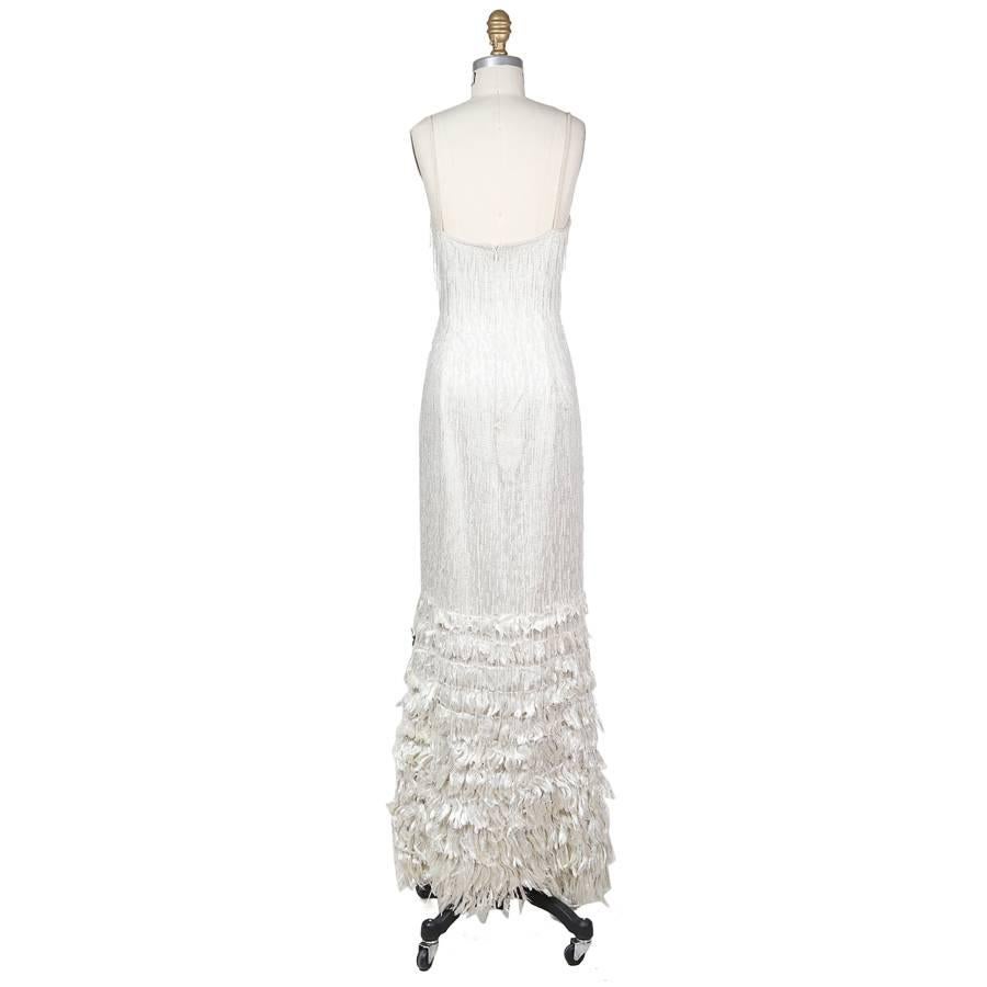 This is a gown by Todd Oldham from fall 1994.  It is white silk covered in vertical threading and beaded fringe.  The spaghetti straps are beaded and the bottom of the skirt also features a white fray in tiers.  The closure is an invisible zipper