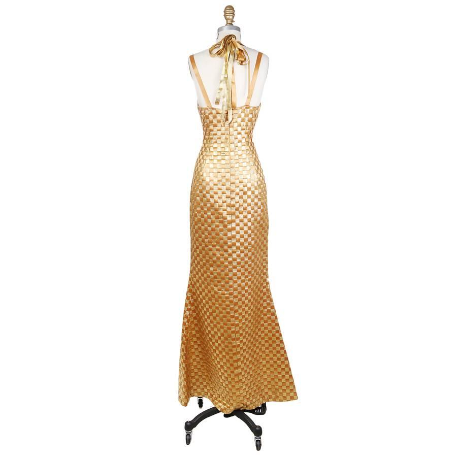 This is a long sheath cut gown by Todd oldham from .  It features a smooth shiny gold and textured gold ribbon checkerboard weave.  The wide ribbon used to create the weave are also used for the straps.  The closure is an invisible zipper down the