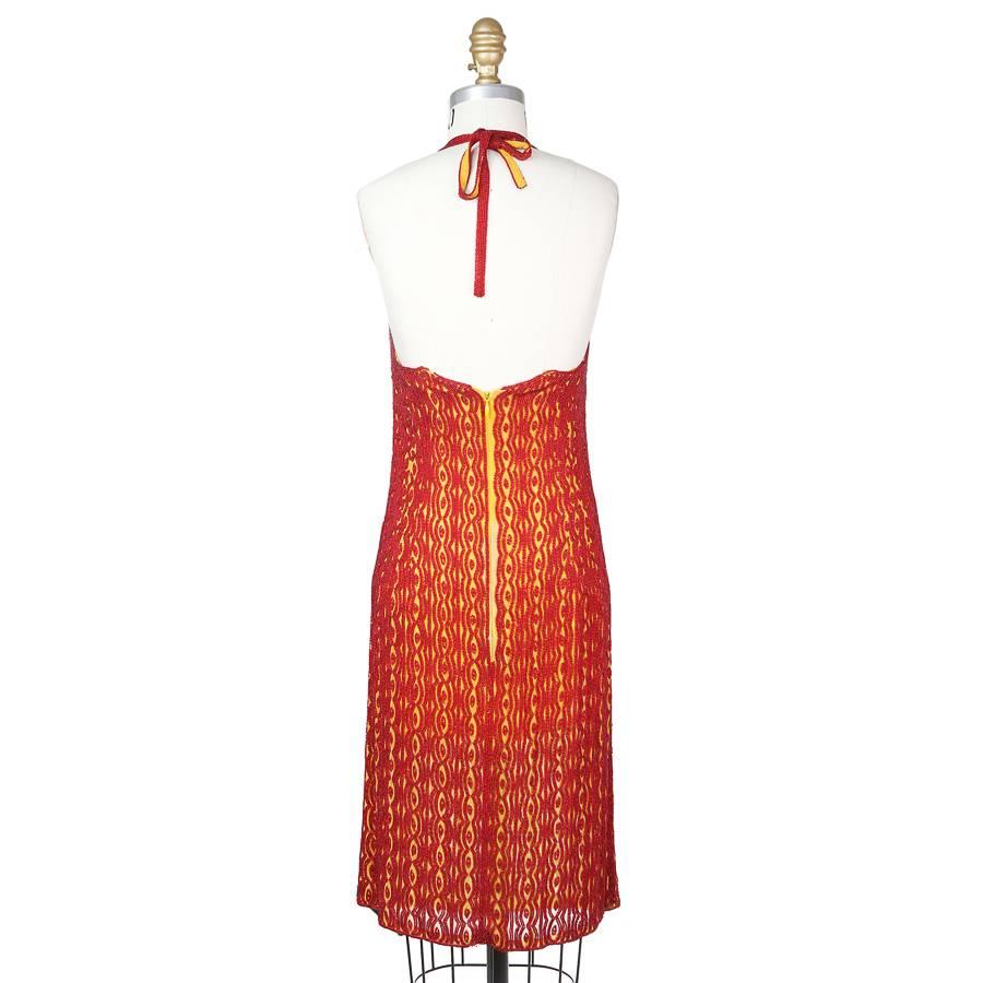 This is a halter neck mini dress by Todd Oldham from the 1990s.  It is made from  a mustard colored shear chiffon and covered in a design of ruby red beads.  the closure is an invisible zipper down the center back with a top hook and eye closure.