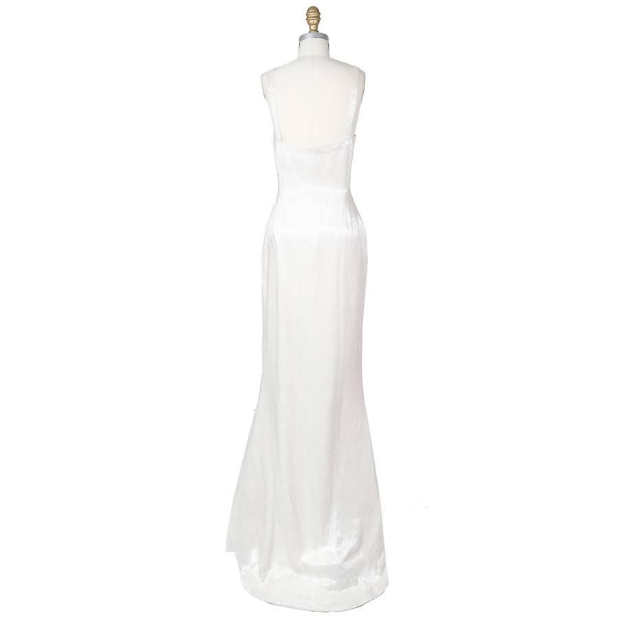 This is a white gown by Todd Oldham from fall 1994.  It is made from white silk and covered in translucent bugle beads, including the straps.  The closure is an invisible zipper down the back.