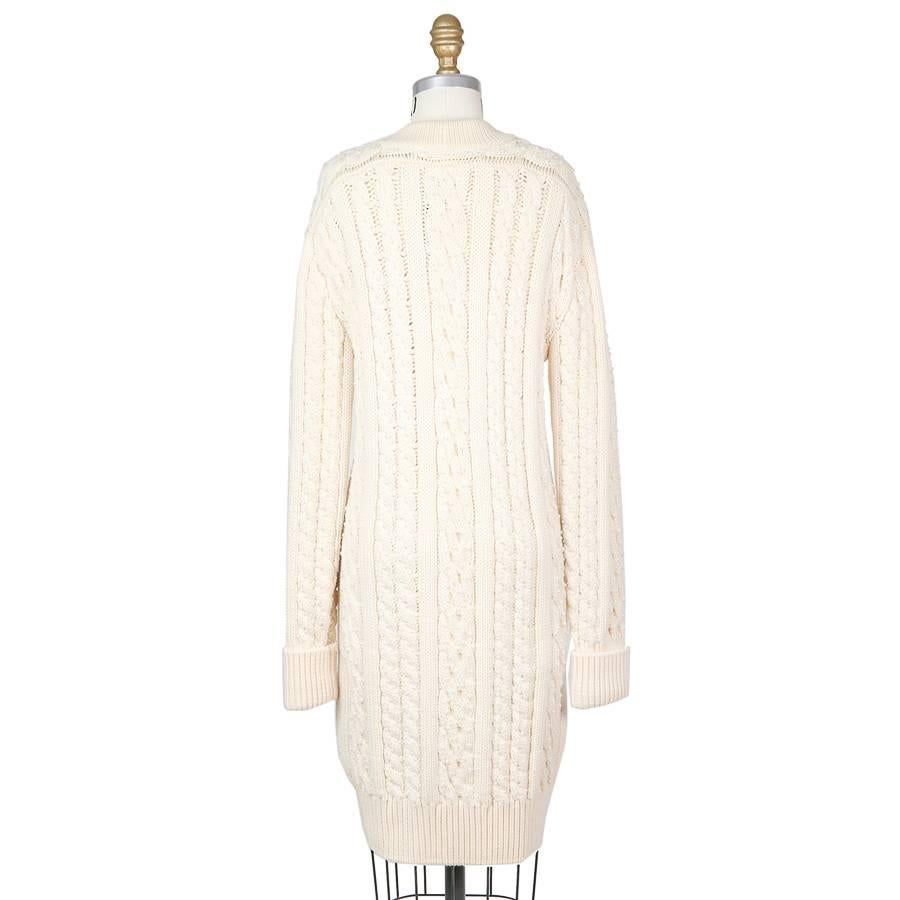 This is a cream colored merino wool cardigan by Chanel c. 1990s.  It features small pearls sewn into the cable knit.  The gold buttons say 