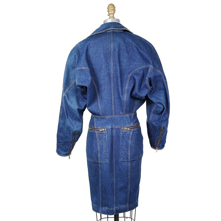 This is a medium blue denim coat dress by Azzedine Alaia c. 1980s.  It features a full length asymmetrical zipper that allows the dress to be open or closed and is similar to a motorcycle jacket closure.  It has dolman sleeves with zippers on the