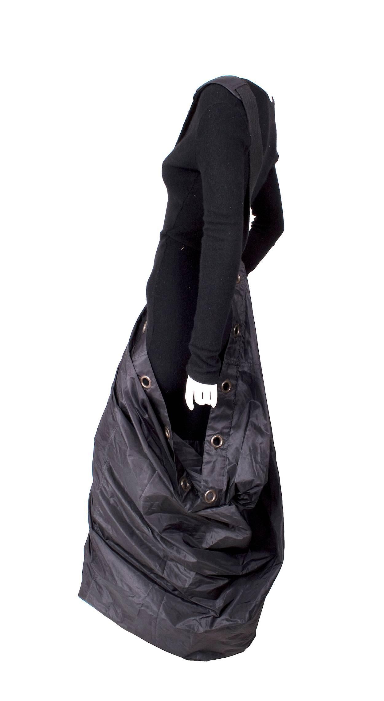 This is a dress by Jean Paul Gaultier c. 1990s.  The body is a black cashmere knit sweater and has a black nylon skirt with large grommets that is held up by a canvas shoulder strap.  

18" shoulder to shoulder
27" long sleeves