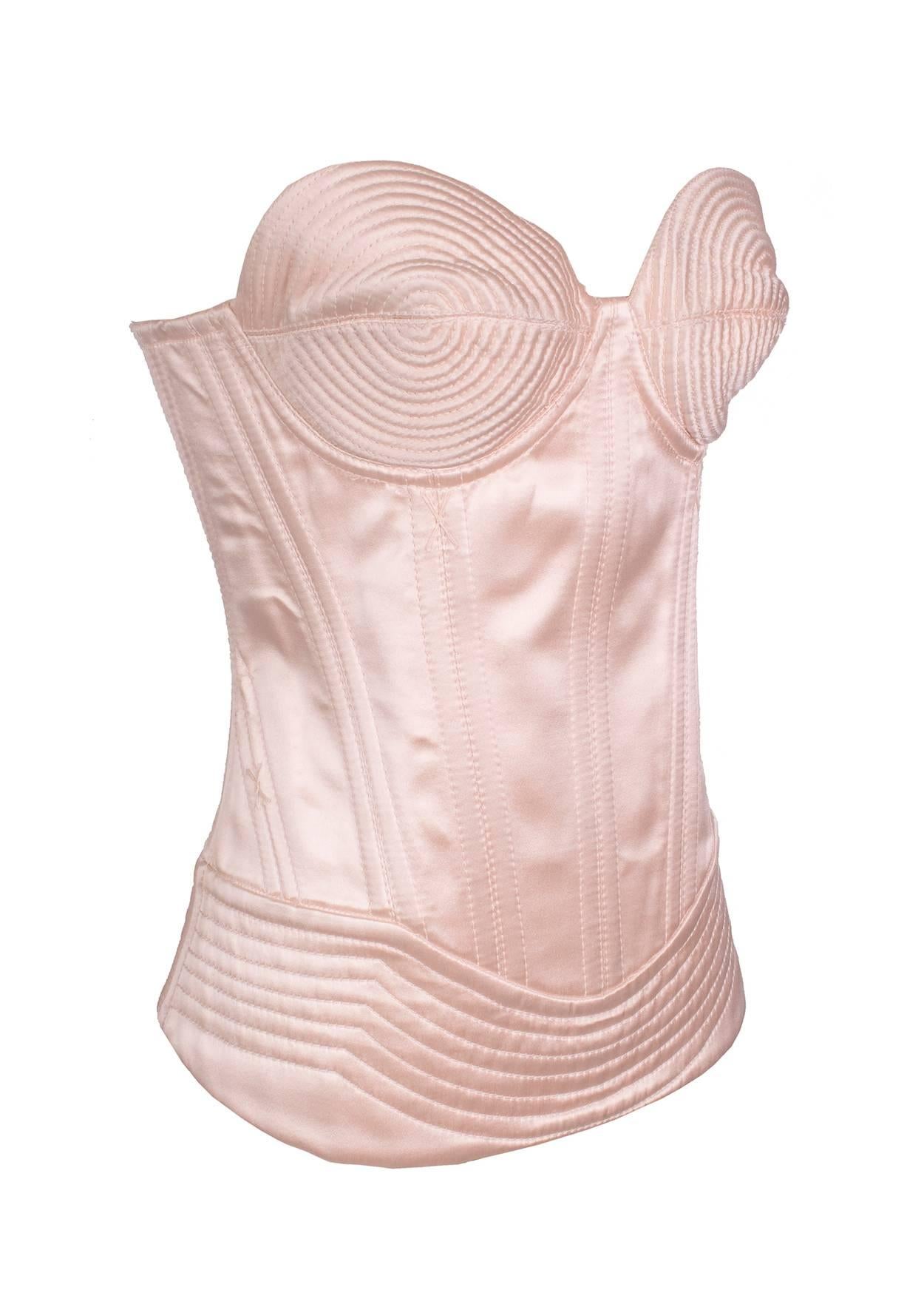 This is a corset by Jean Paul Gaultier c. 1980s.  It features sculptured cone bra cups and laces up in the back.  There is also a side zipper closure.  