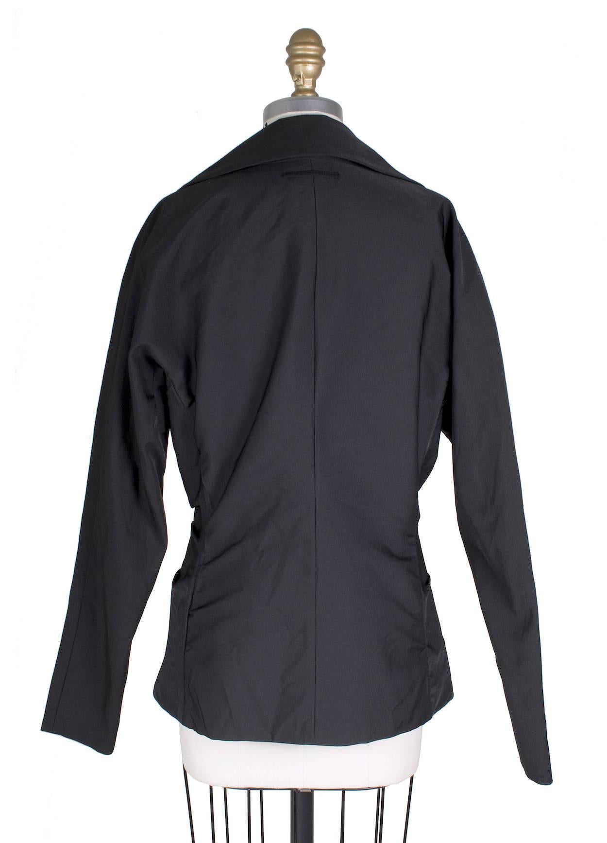 This is a contemporary jacket by Jean Paul Gaultier.  It features a knot in front and has a raglan shoulder and front zipper closure.