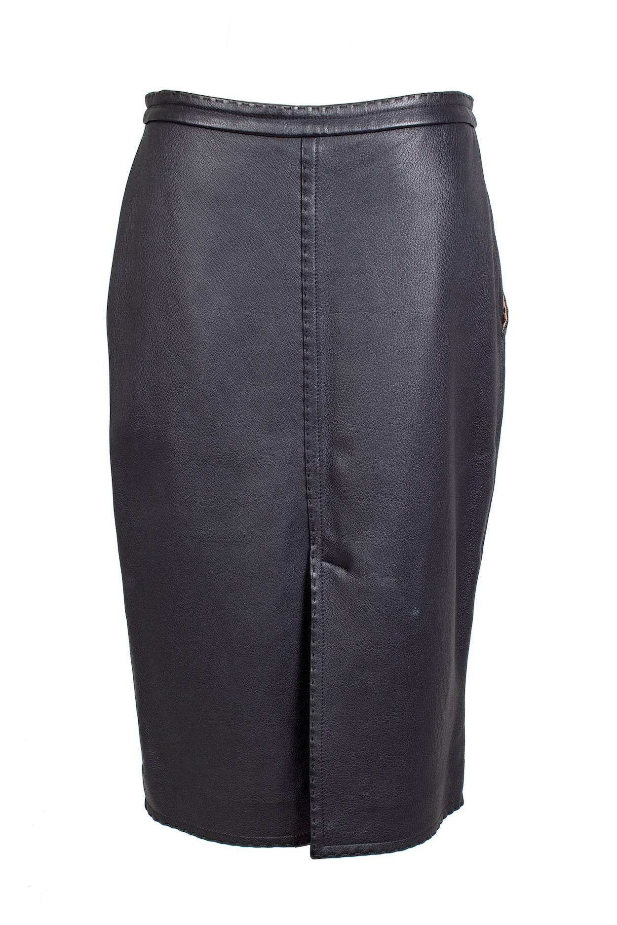 This a leather pencil skirt by Jean Paul Gaultier c. 1990s.  It features exposed stitching, a front zipper and button closure, and two waist pockets.  Lined in copper colored satin.