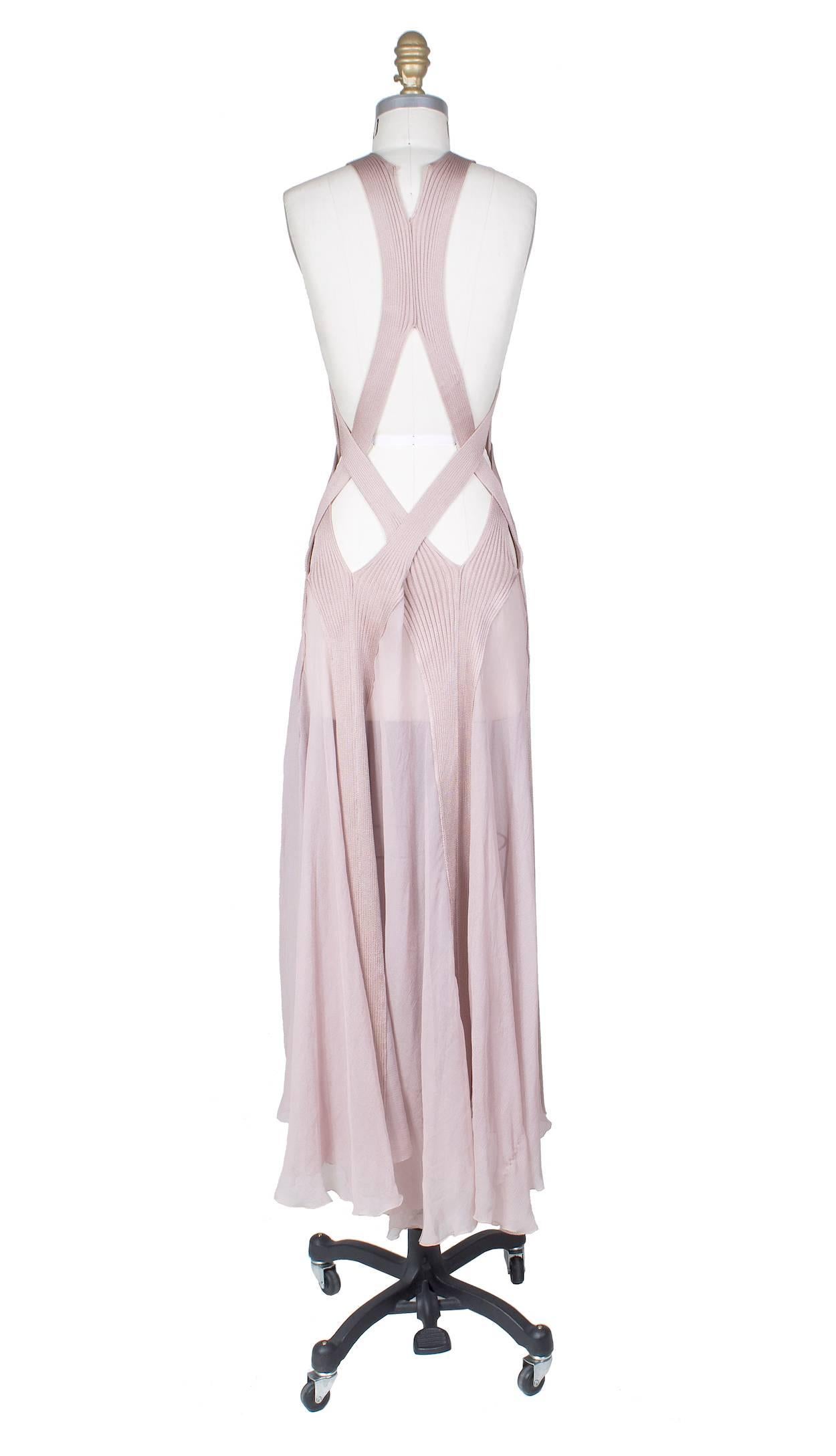 This is a dress by Jean Paul Gaultier.  It is made of multiple ribbed knit bands and straps that wrap around the bust in combination with a sheer pink chiffon.  