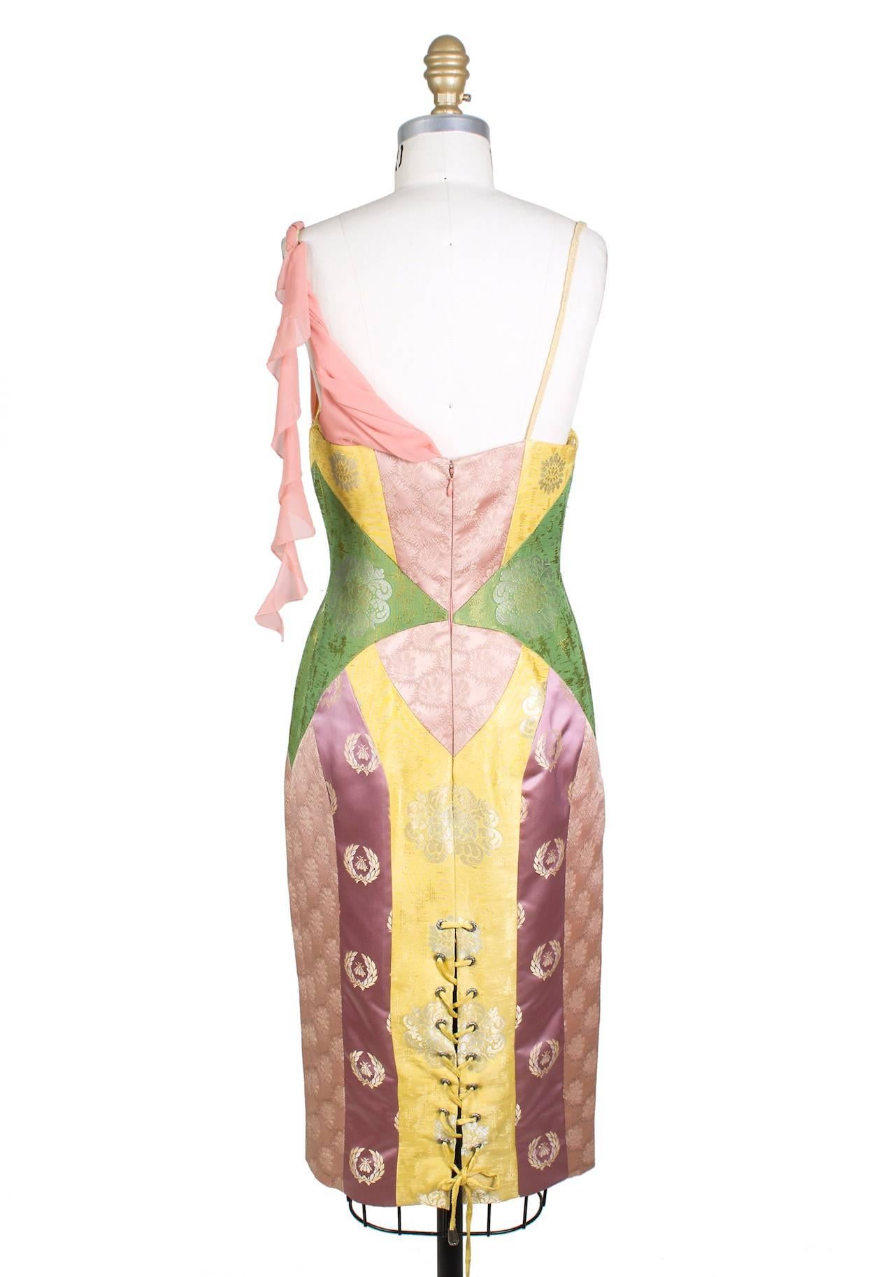 This is a sheath dress from Versace circa 1980s/1990s. It features pastel colored panels of brocade fabric and has lace and chiffon draped details around the bust.  The back has a corset lace up slit in back.  