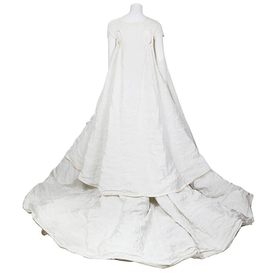 This is a modern wedding dress by Olivier Theyskens for Rochas.  It comes with a long cap sleeve jacket and features a sculptural flower in the center of the bust.  

Please inquire for size/measurements.