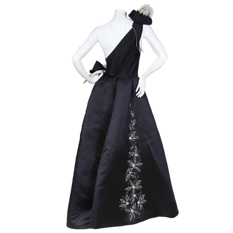 This is a navy blue gown by Nina Ricci circa 1960s. It features one shoulder and a sweetheart neckline. There are white floral details that begin from the shoulder and continue around to the waist and cascade down the skirt. 

Nina Ricci 
Waist-14.5
