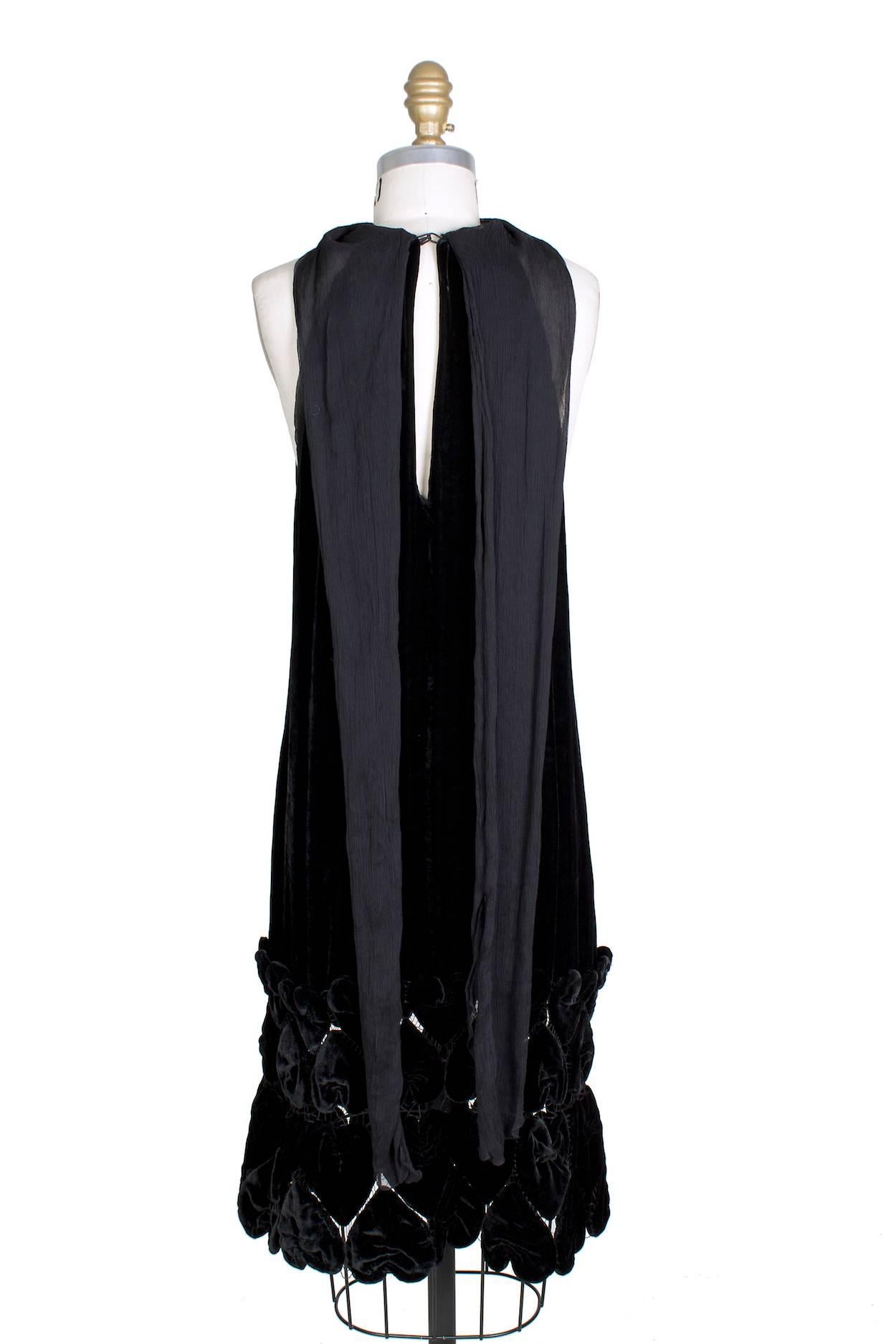 This is a velvet dress by Jean Paul Gaultier c. 1990s.  It features an attached chiffon scarf around the neck and the bottom of the skirt has loosely stitched together large velvet pieces to create transparency.  