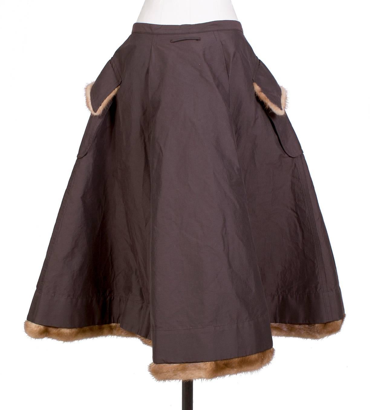 This is a circle skirt by Jean Paul Gaultier from his Fall 2005 Couture collection.  It features pockets and mink fur trim on the pockets flaps and the hem.  The closure is a front snap waist closure.