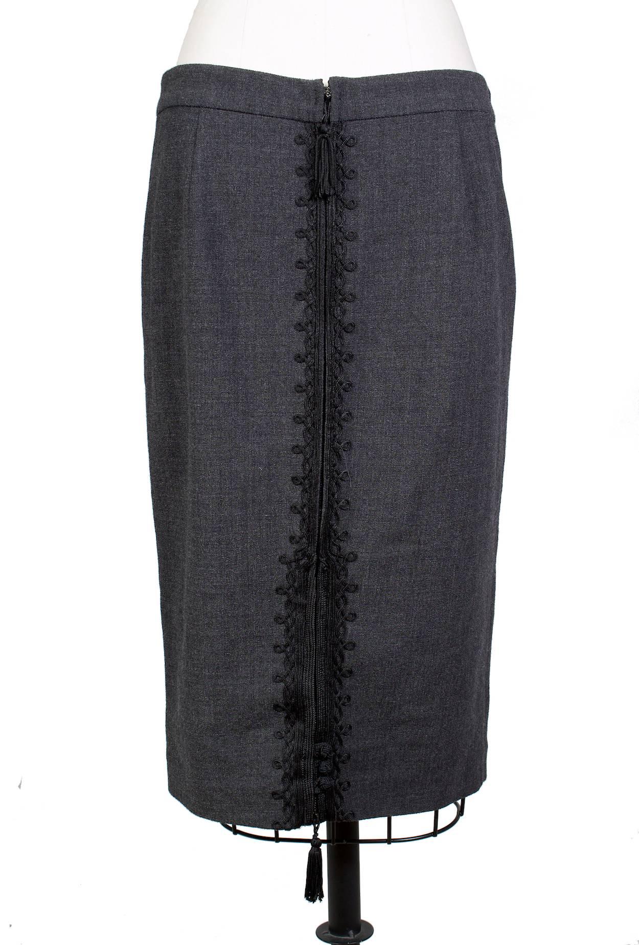 This is a grey wool pencil skirt by Jean Paul Gaultier c. 1990s.  It features a full length double zipper down the back ornamented by a black decorative embroidered trim and tassels.