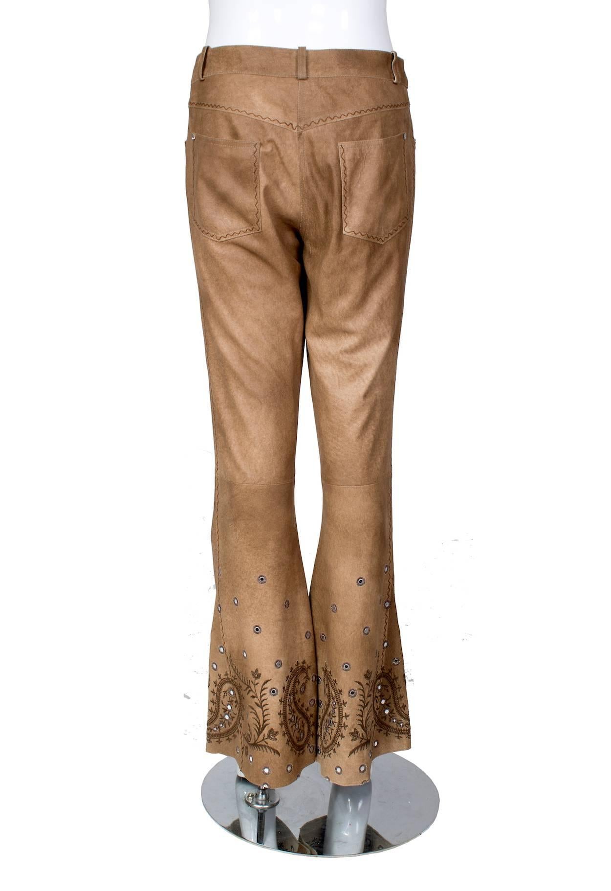 These are a pair of pants by John Galliano for Dior circa early 2000s  They are made of brown suede and feature zig zag stitching and embellished paisley design around the bottom of the legs.  

9