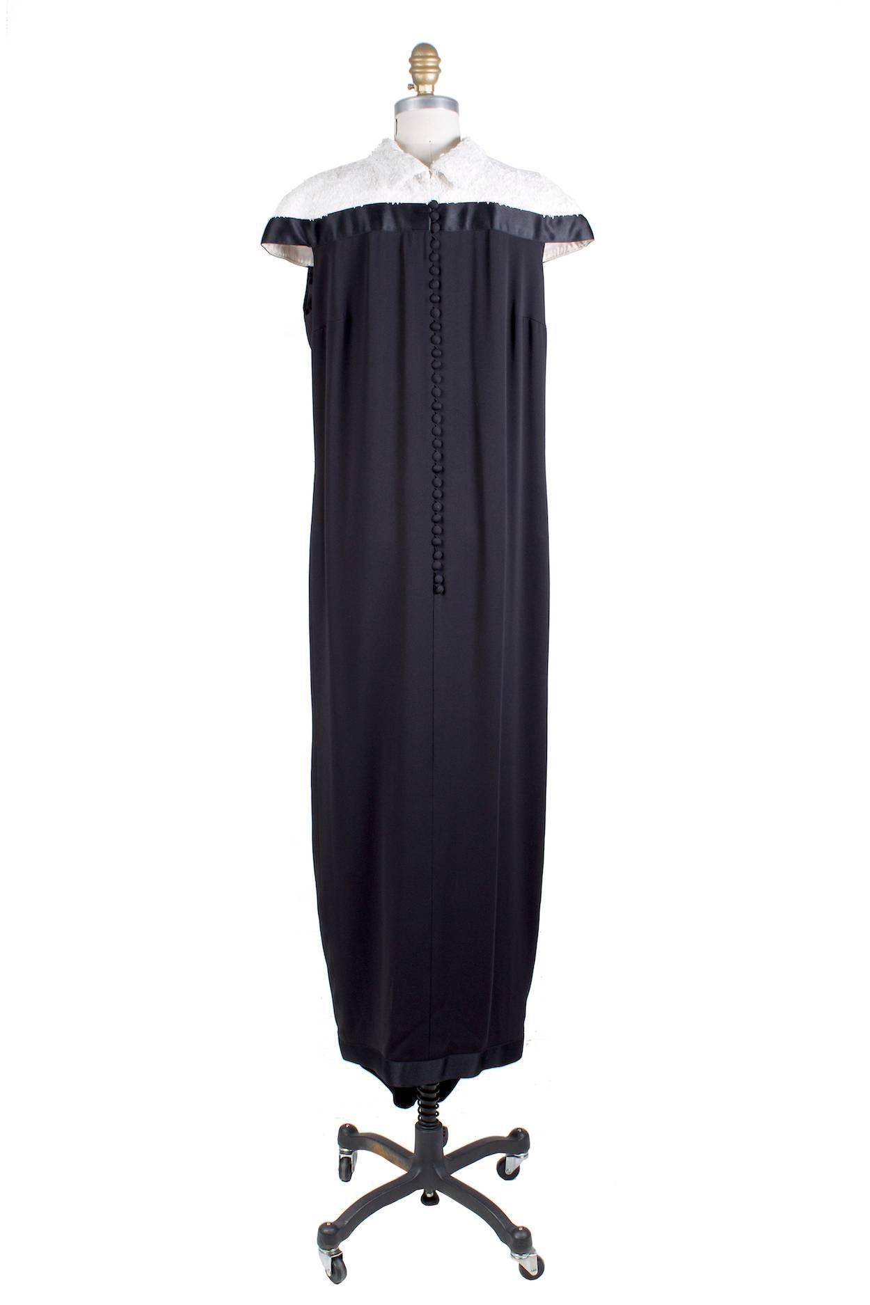This is a long dress by Chanel.  It features an embellished collar consisting of tiny leaf shaped sequins.  There are silk covered buttons down the back and a slit in front that also closes with silk covered buttons.  The skirt also has a crepe