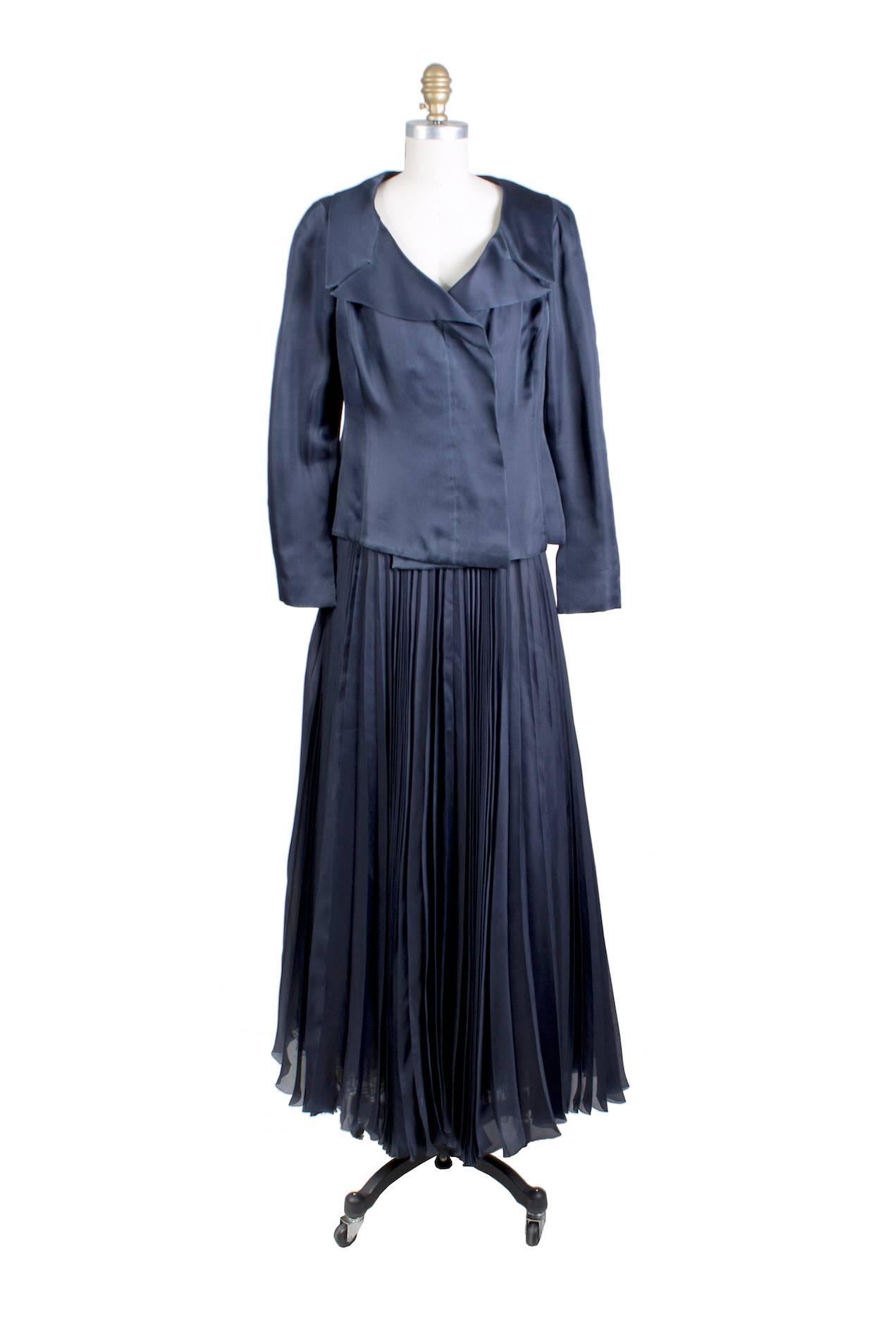 This is a couture dress by Chanel c. 2000s.  It features a pleated skirt and the dress comes with a matching jacket.  Made from layers of sheer navy blue silk and it has a mesh and tulle lining in the skirt.  Couture serial number is