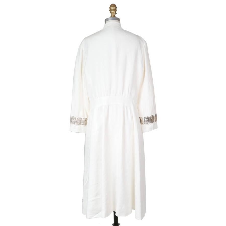 Contemporary linen coat by Vivienne Tam.  It features rectangular antique silver plates with Buddha imprint along the front and on the cuffs.  It has a mandarin collar, front snap closures over the bust, and two front pockets.

15