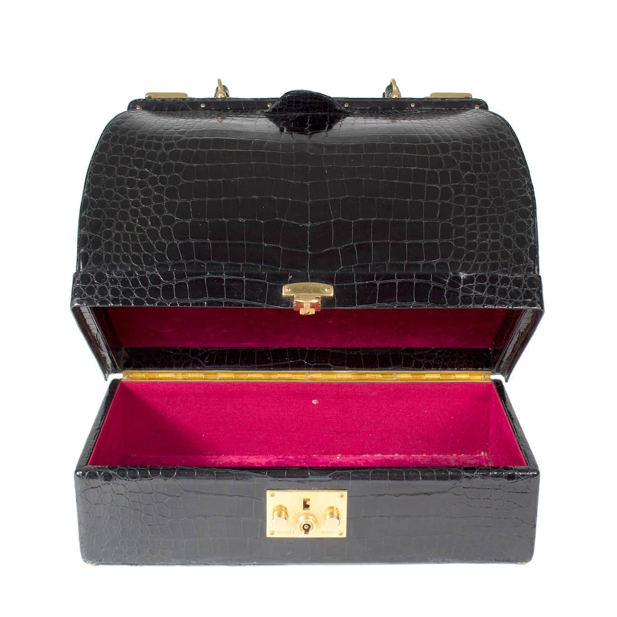 Il s'agit d'un sac Sac Mallette en croco d'Hermès c. années 1950/1960. C'est un sac de style docteur avec un compartiment à bijoux au fond. Il est doté de deux fermetures coulissantes supérieures:: d'une poignée supérieure et le compartiment