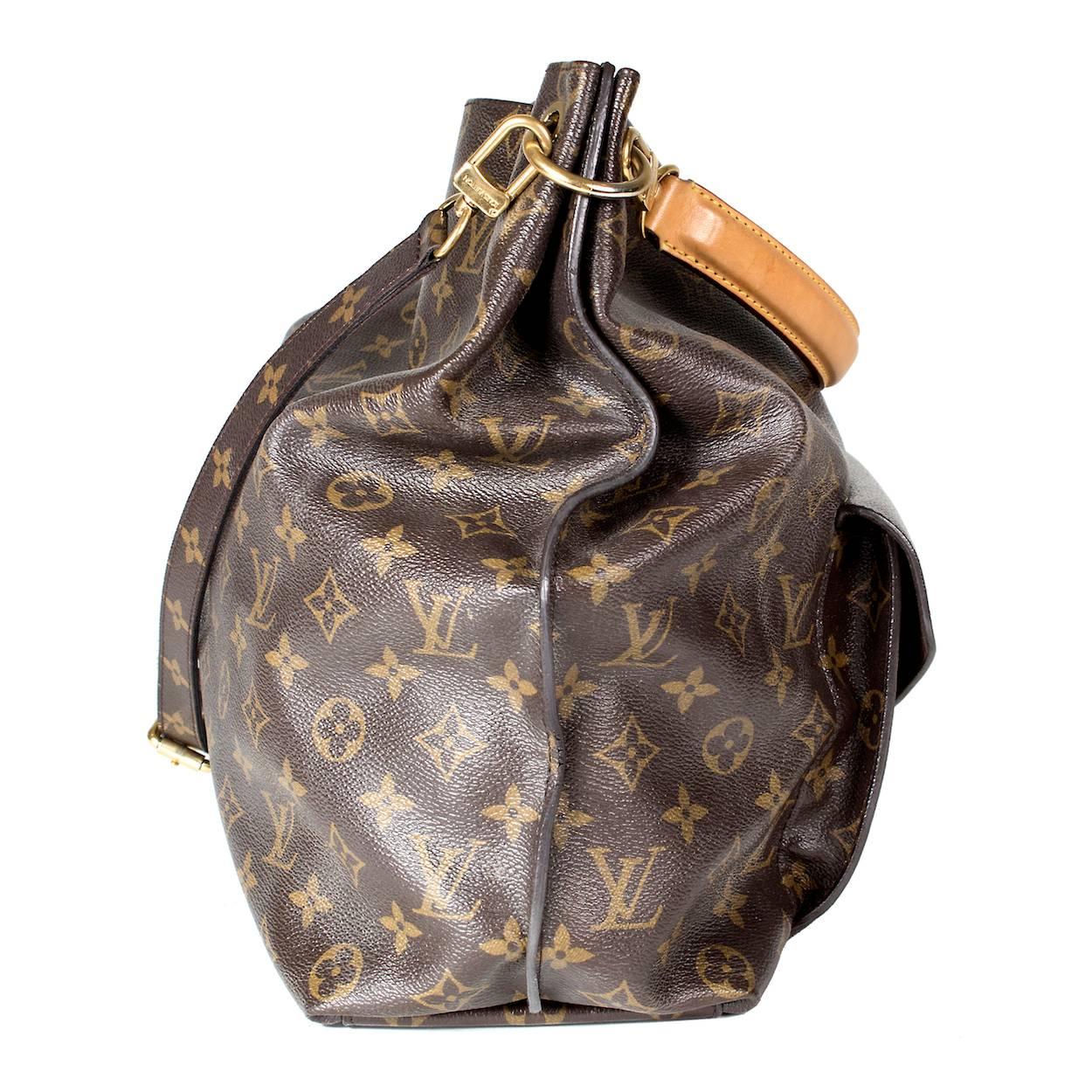 This is a contemporary leather monogram bag by Louis Vuitton.  It features a top handle as well as an adjustable shoulder strap.  It has an open top and the front features an envelope shaped pocket with gold lock clasp.  It is lined in brown suede