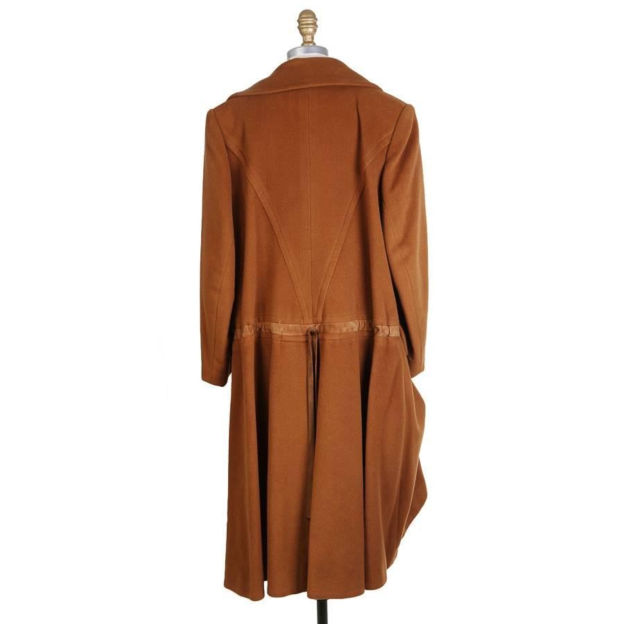 This is a cashmere coat by Hermes.  It features two front waist pockets, single breast closure, and a hook drape in front.  The coat also has a back cinch tie sewn into the jacket.  Lined in silk.  

17.5