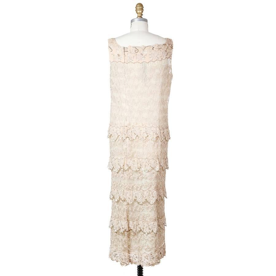 This is a vintage dress by Pierre Balmain.  It features scalloped tiers for the skirt and the dress has a beige chiffon under layer with an overlay of beaded, sequined, and embroidered mesh.  Back zipper closure.