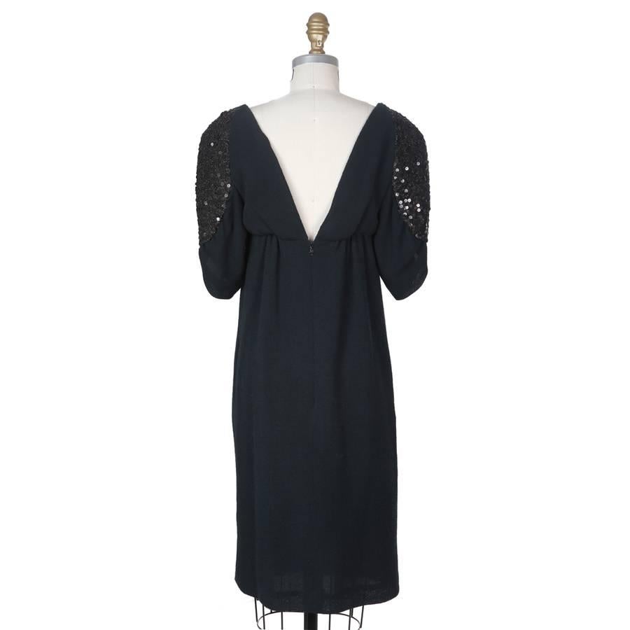 This is a dress from Chanel that features draped and sequined butterfly sleeves.  It has a wool out and is lined in silk.