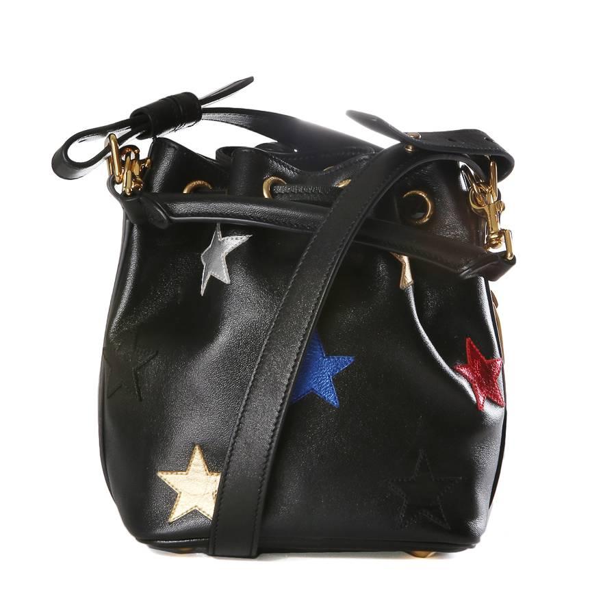 This is a mini bucket bag by Saint Laurent featuring metallic leather stars sewn on.  It ha a top leather drawstring closure and is lined in black suede.  Strap is adjustable between a 21.5
