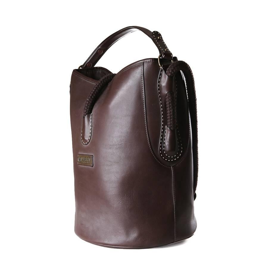 Leather bucket bag by Perrin.  It has a rope handle and a top rope strap magnetic closure.  The inside is lined in nylon and has an inner zipper pocket.

7