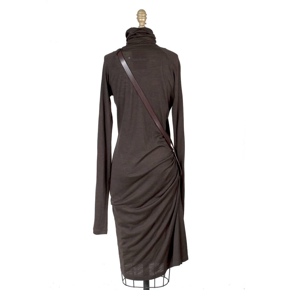 This is a long sleeve turtleneck tee dress by Jean Paul Gaultier.  It is made from a thin stretch cotton and features a leather strap attached to the side that goes over the shoulder.  It also has a side slit.