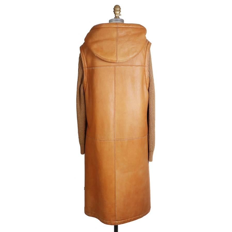 This is a coat by Hermes.  It features tan colored leather and beige wool sleeves.  Lined in shearling, hooded with drawstring. 

19