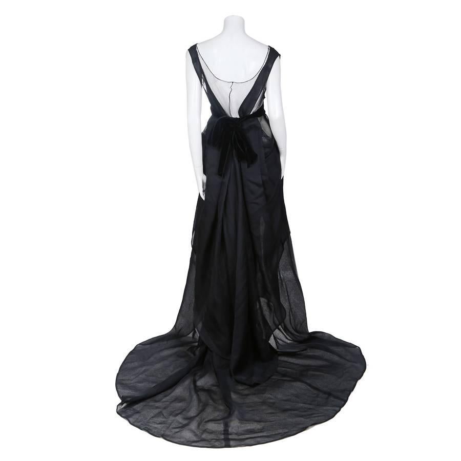 This is a black silk and mesh dress by Tom Ford for YSL c. early 2000s.  It features an under layer of wide mesh over the best with black silk over top, revealing the mesh where the silk does not cover.  The front of the skirt has a high low hem