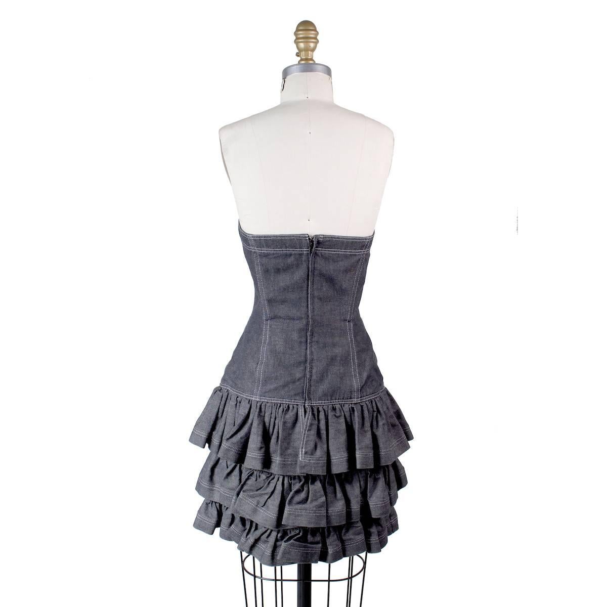 This is a strapless dress by Patrick Kelly circa 1980s.  It features a sweetheart bust and ruffled skirt.  Grey denim with contrast stitching.
