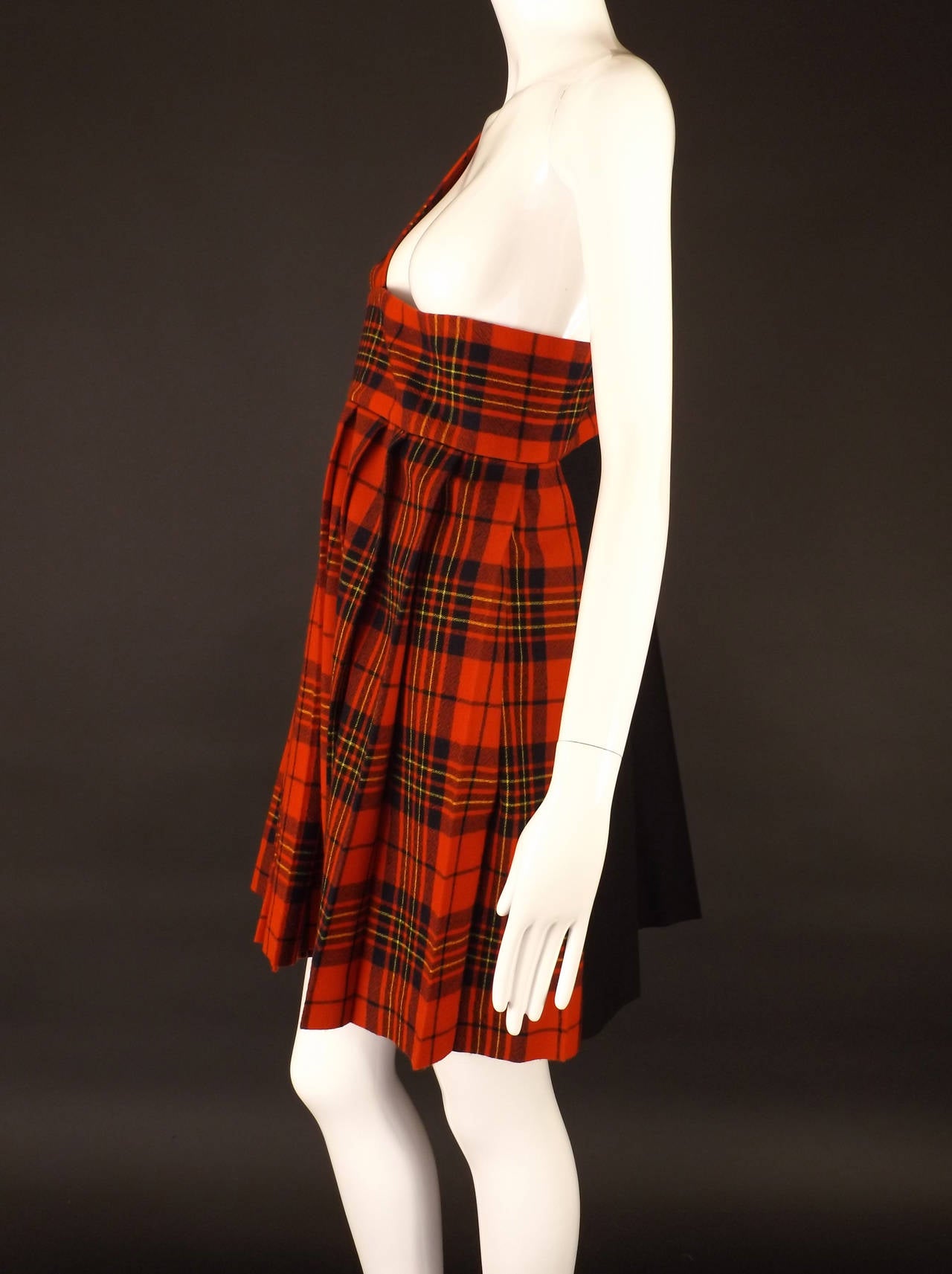 Fall 2011 Collection for Tricot. The one shoulder jumper is in red wool plaid with a contrasting flat black wool. Wide shoulder strap connects a wide band across the top. The skirt of the jumper is entirely in side pleats. No closures and unlined.