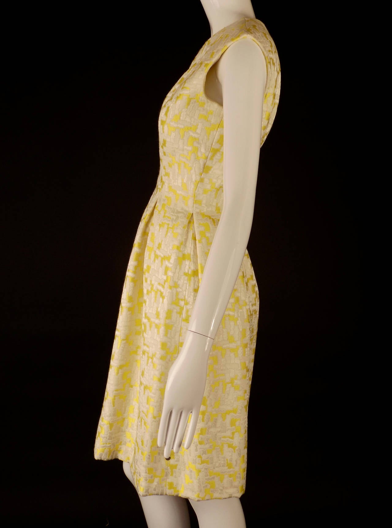 Fantastic 1960s ensemble consisting of a spring dress and coat. The fabric is a gorgeous satin brocade in white with a lemon yellow background. The dress is princess seamed and with a seam down the center front that all open to inverted pleats into