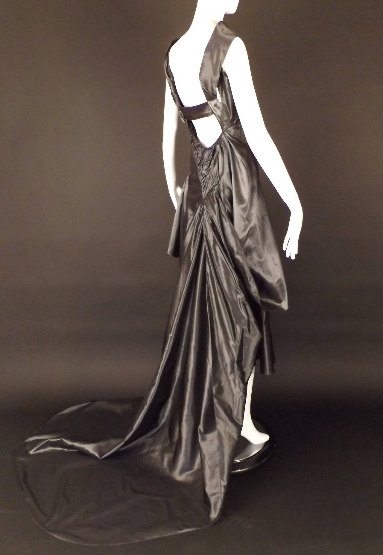 Fantastic evening gown in a pewter silk taffeta. The gown has a draped, bias neckline with a single shoulder strap on the right side. The dress is dart fitted at the bust and has button and loop closures down the right side seam.  The dress has very