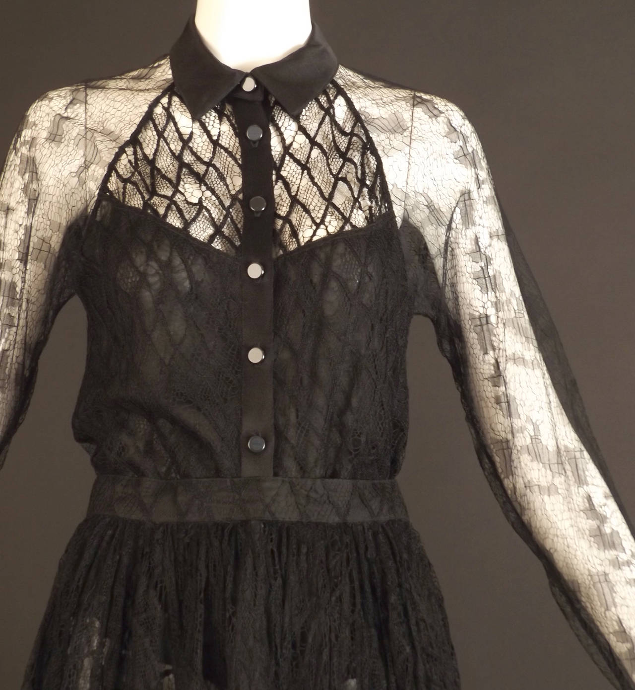 Wonderful c.1990s 2pc dress in black lace. The blouse has a black silk satin collar and button closures down the front silk placket.  The body of the blouse is a spider web lace with a larger diamond pattern. The chest yoke is unlined while the body