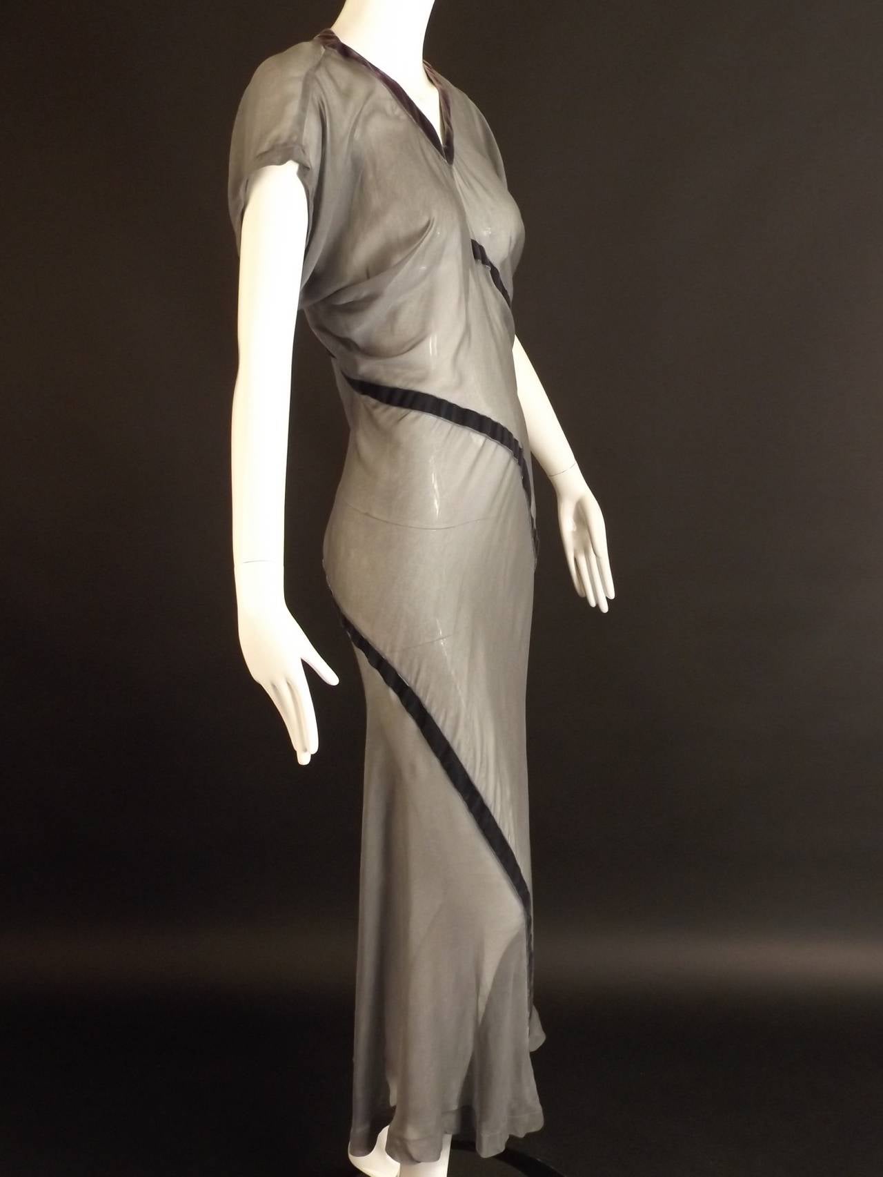 Late 1990s evening or maxi dress in a faded gray rayon chiffon that is cut on the bias.  The dress has 2 dark gray velvet ribbons that circle the dress, but what is amazing is the ribbons are actually hiding the seams of the construction. It's