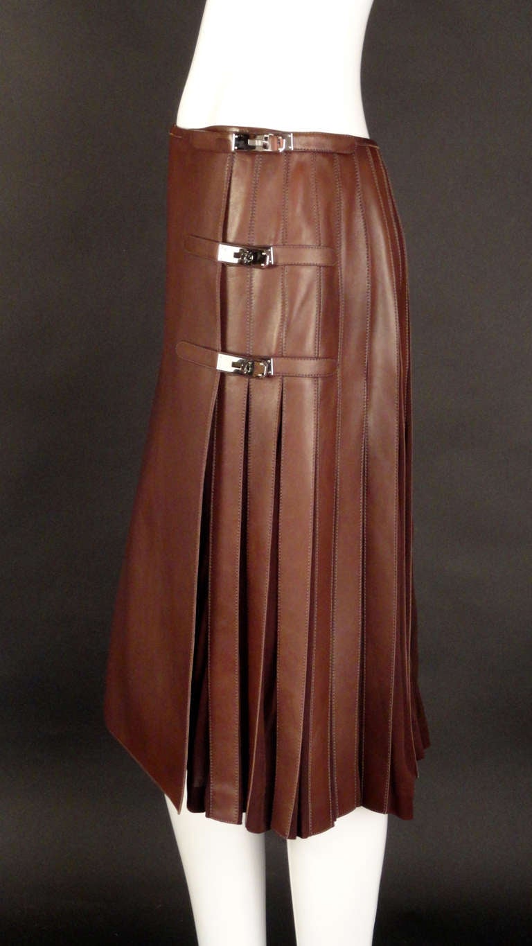 Stunning wrap skirt in a buttery soft brown leather appliquéd over pleats of a brown silk jersey knit.  Center front panel in leather with the pleats around the sides and back.  Silver turn key hardware fasteners down the side.