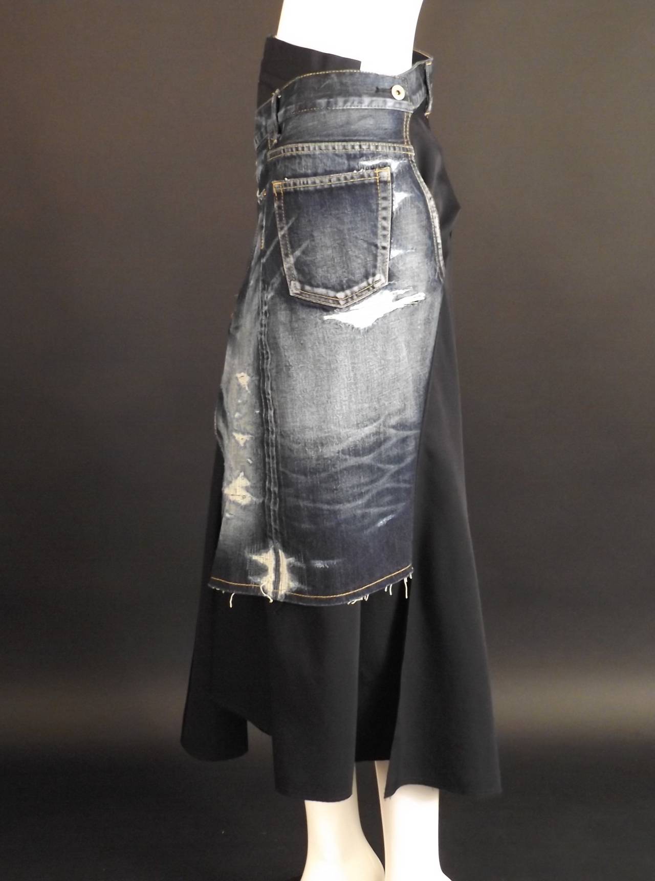 Spring, 2014 Runway Collection. Fantastic deconstructed and distressed denim blue jeans and integrated into a black wrap skirt. The skirt goes around the waist and hooks the wrap portion circles the back and button to the left side front.