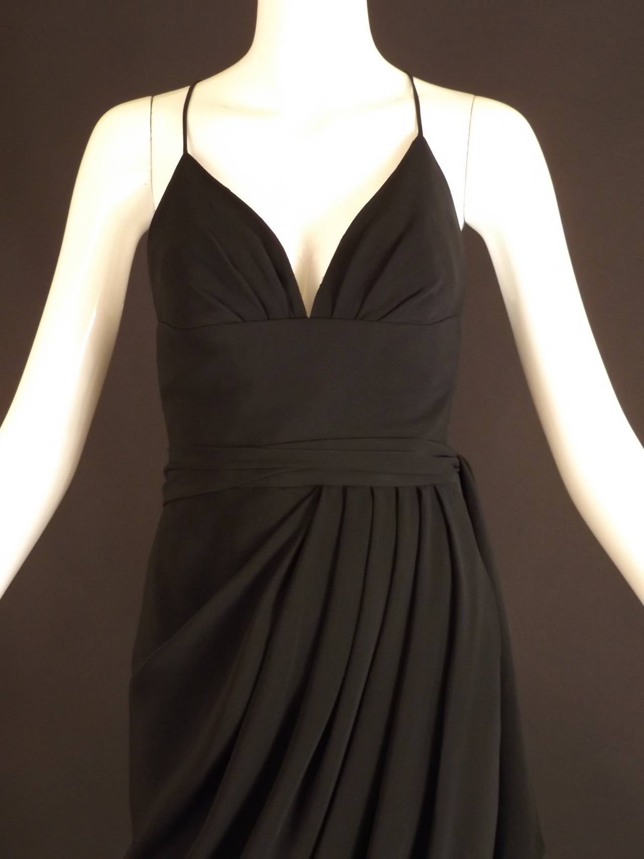 Gorgeous evening dress in black crepe dating just before his death, which was 1972. The dress has a pleats pointing upward to the bust and criss cross spaghetti straps on the bodice. Wide midriff yoke falls to the natural waistline seam.  The wrap