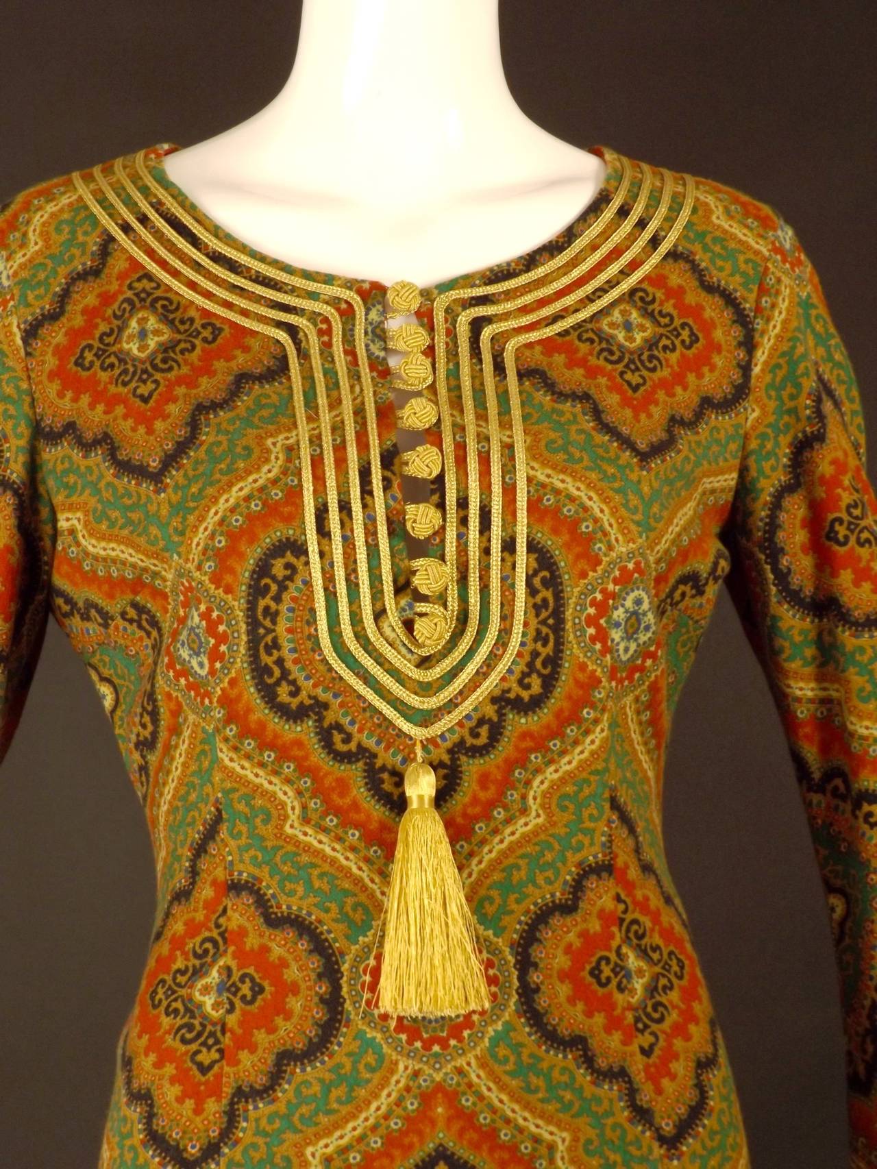 Gorgeous ethnic style dress from the 1990s to early 2000's. The dress is a very soft wool with a pattern in black, red, gold, green, blue and white. God ribbon trimmed neckline with French knot and loop buttons down the front slit. A gold tassel