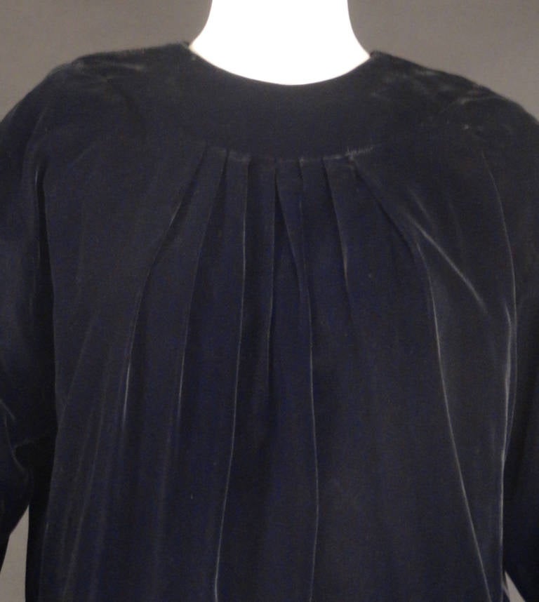 Fabulous, numbered, Haute Couture dress from the 1980s in black cotton velveteen. The sac style dress has a scoop neckline with a chest yoke and pleats falling down the center front and back. The bodice ends in gathers and bubbles to the dropped