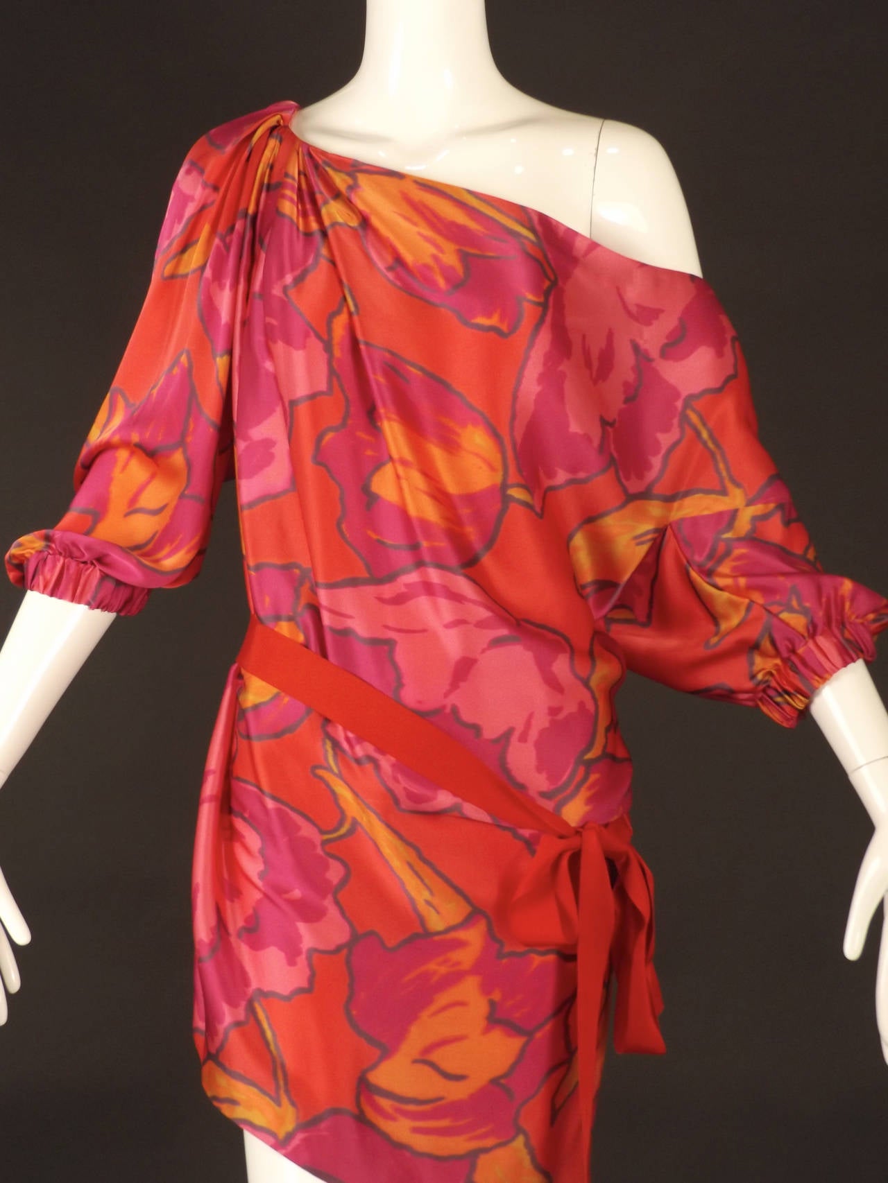 Summer, 2010 Runway Collection. This fabulous dress is in a pink, orange and black printed silk satin. One shoulder with pleats falling from the shoulder and draping the fabric down the body of the dress. Elastic gathered bands at the base of the