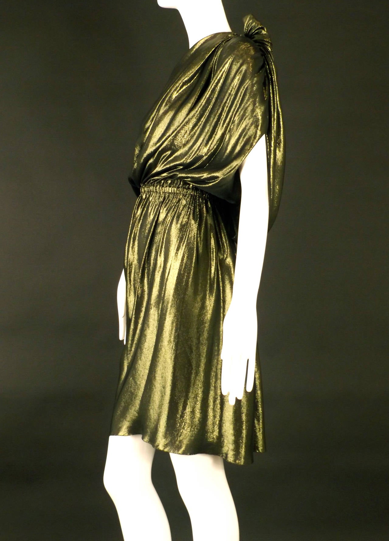 Perfect for the holidays! This gold and green silk blend lamé dress is from the summer, 2010 runway collection.  The dress falls with pleats from the left shoulders  to the elastic gathered waistband. An over drape also falls from the left shoulder