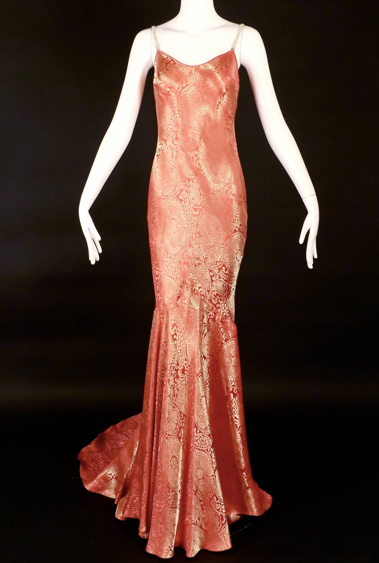 Stunning evening gown from the Spring, 1999 RTW collection. The gown is in a  deep pink and gold floral silk blend brocade. The bias cut gown  has a plunging neckline with rhinestone shoulder straps. Single seam across the back waistline.  Large