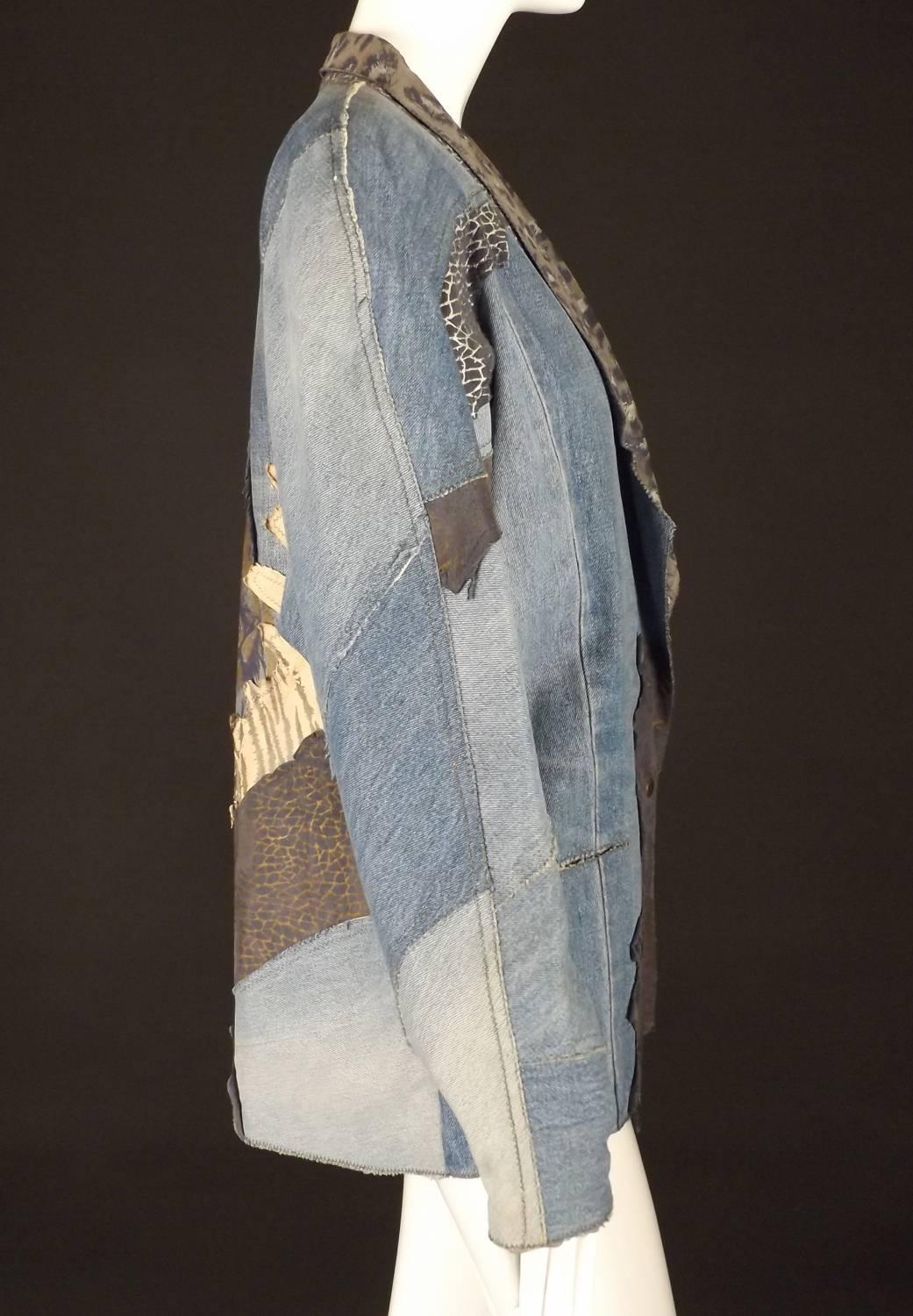 Awesome oversize 1980s stone wash jacket in blue denim and animal printed leather appliqués. The jacket has a shawl collar and notched lapels in leather.  V-shaped from the built up shoulder pads to the waist and hips. Inset pockets on the from