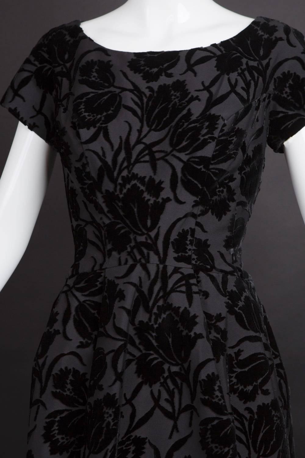 Wonderful little 1950s day or dinner dress in a silver velvet & twill brocade. The sheath dress is princess seamed through the bust with pleats opening from the waistline seam into the hips. Scooped neckline and a sweetheart neckline in back. Center