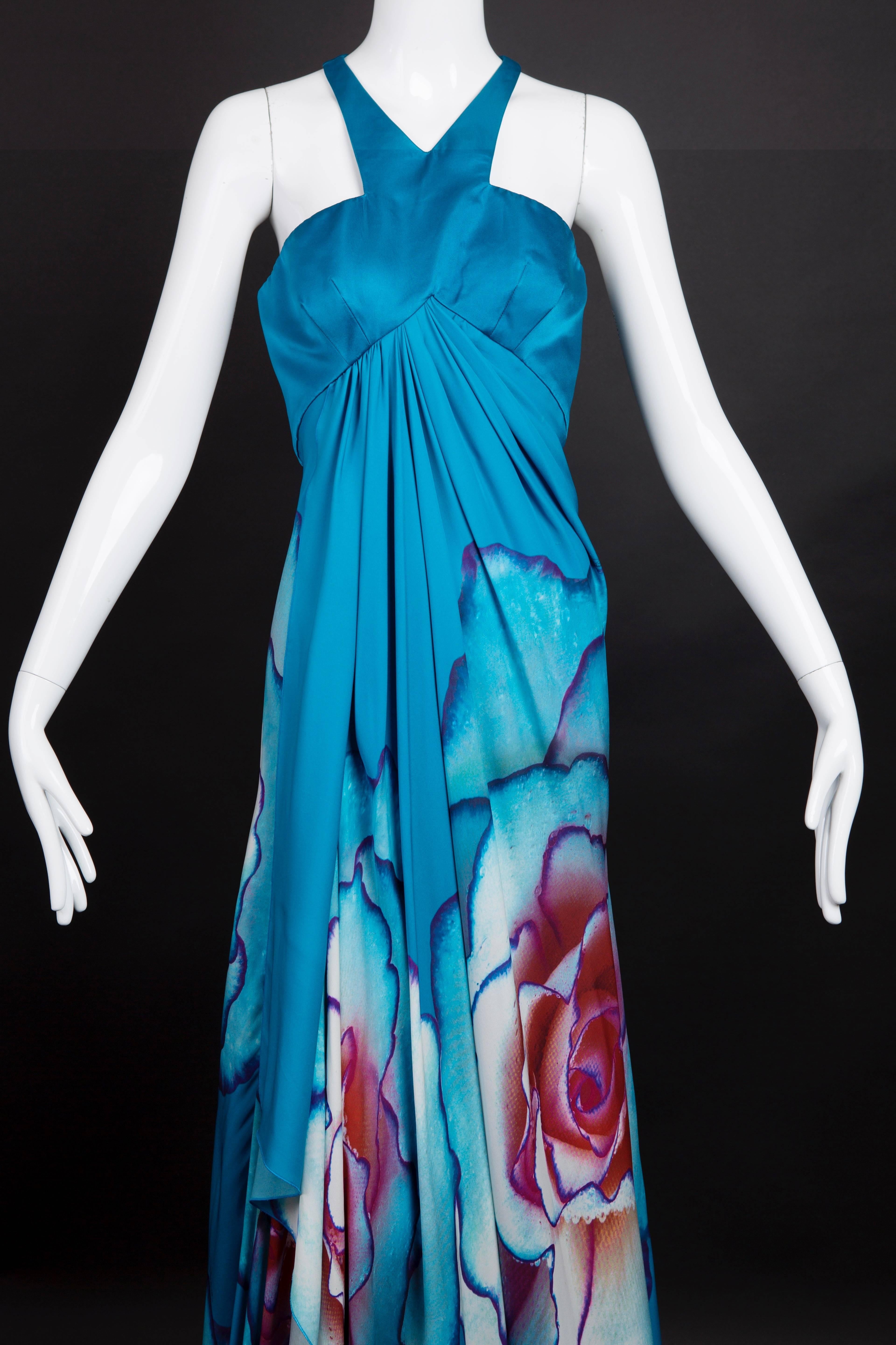 Stunning evening gown in a teal silk satin bodice and a flowing floral print skirt. The wrap from skirt falls in gathers from the raised waistline seam. The skirt is also teal with a large white, purple, blue and mulberry floral print. Zipper