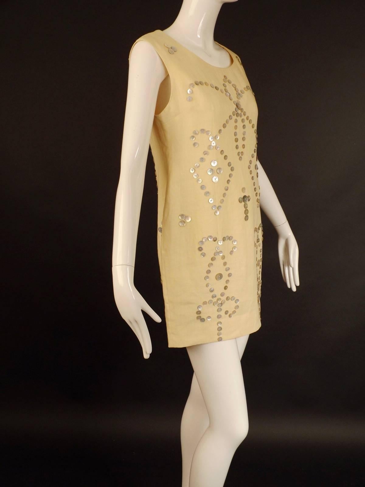 From the 1991 Spring Collection comes this wonderful little sheath dress in ivory linen and covered in a wonderful design of mother of pearl buttons.  The dress has a scoop neckline and is dart fitted at the bust and through the waist and hips, also